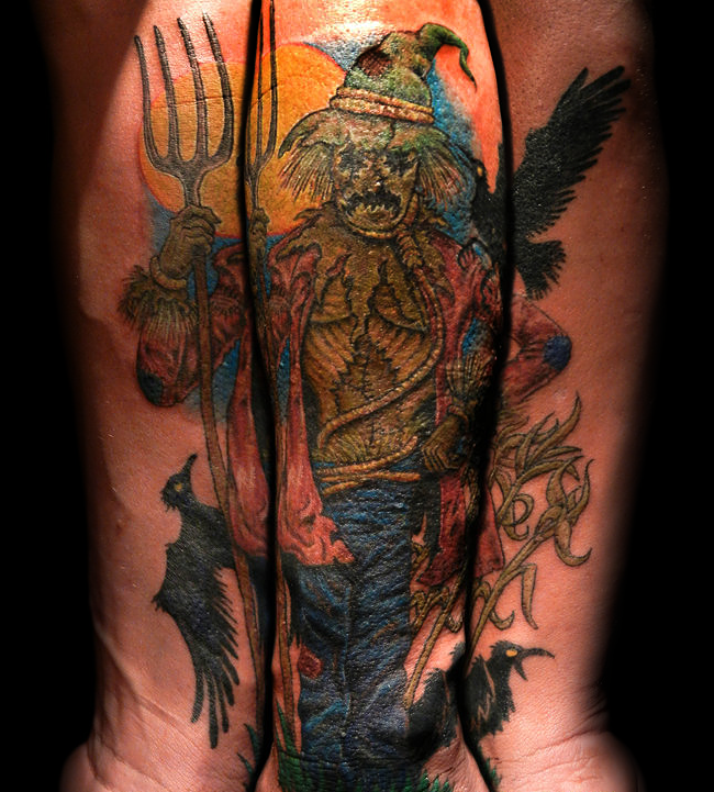 Incredible looking multicolored forearm tattoo of scarecrow with black crows