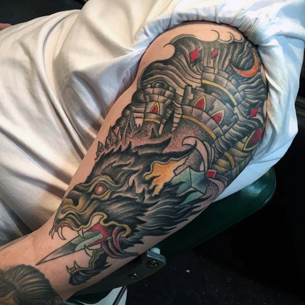 Tatuaje en el brazo, castillo y dragón perforado por la espada