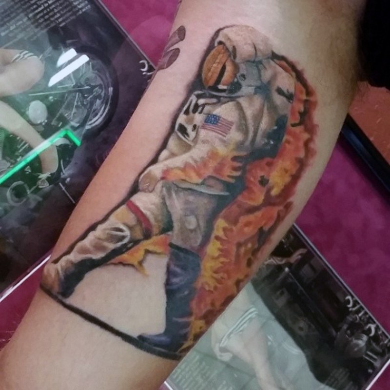 Tatuaje en el brazo, astronauta americano en llamas