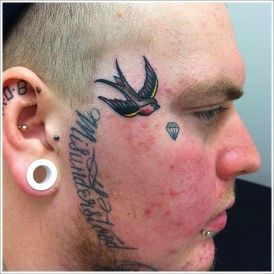 Inscription and swallow face tattoo