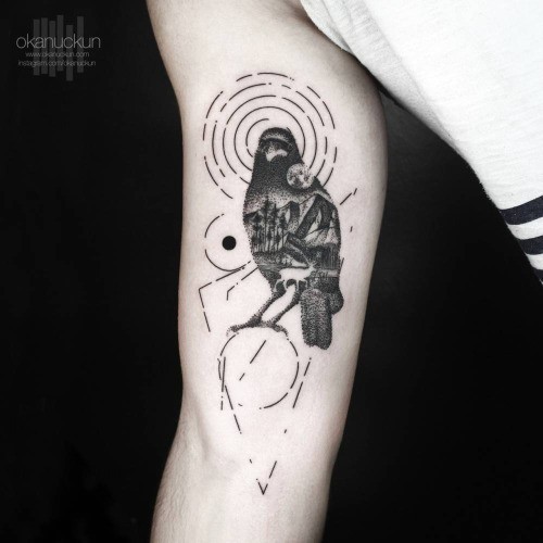 Interesting black ink mystical crow tattoo on arm stylized with geometric figutes