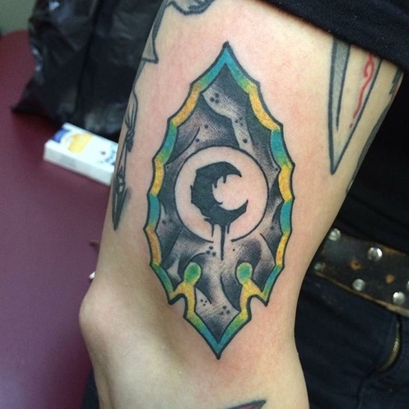 Interesting colored big fantasy arrow head tattoo on arm stylized with moon