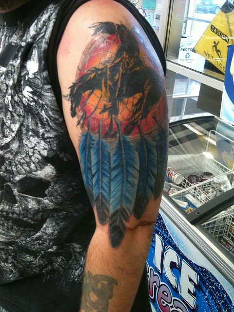 Tatuaje en el brazo, atrapasueños multicolor y hombre a caballo