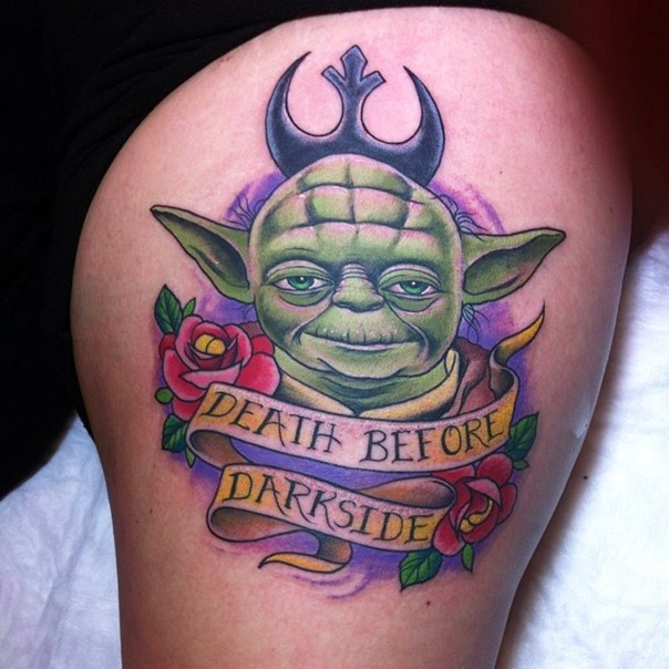 Interesting combined and colored little Yoda tattoo on thigh stylized with lettering and flowers