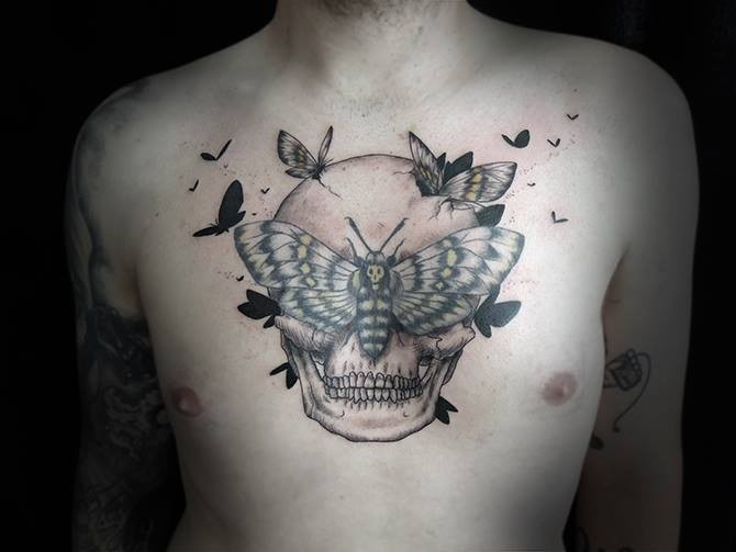 Interesting combined colored human skull tattoo on chest with butterflies