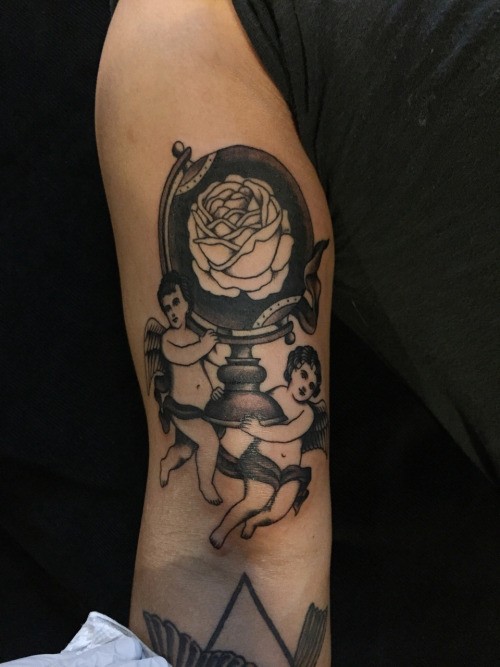 Interesting looking black ink arm tattoo of angels holding globe with rose