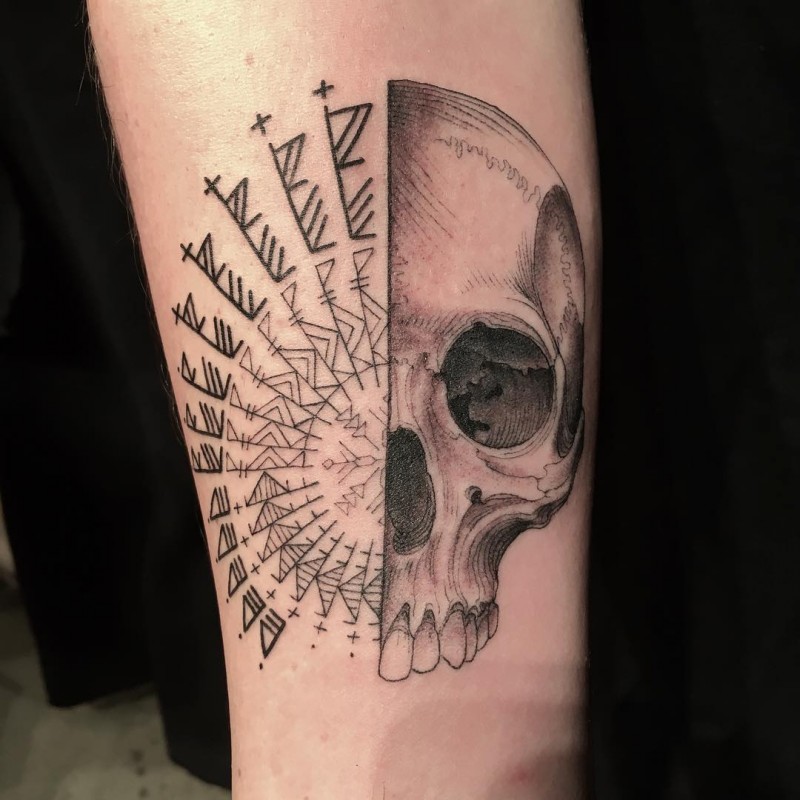Interesting looking colored black ink forearm tattoo of human skull with interesting paintings