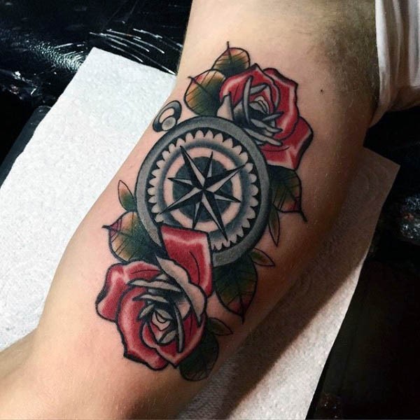 Interesting nautical themed tattoo of compass with flowers on biceps