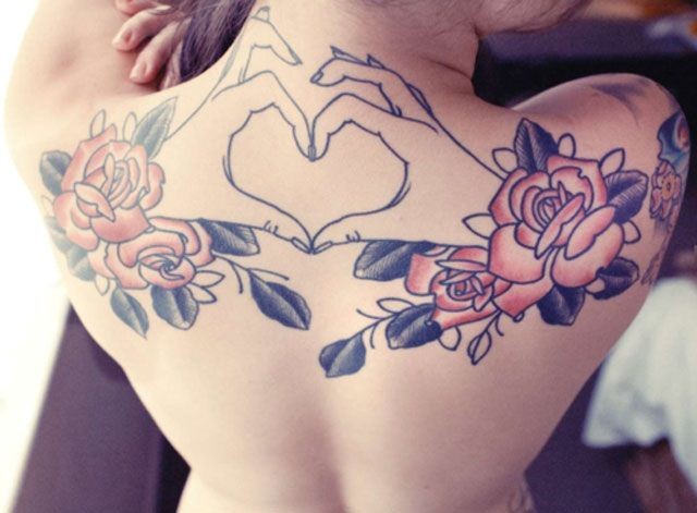 Interesting themed colored flowers with heart shaped hands tattoo on upper back