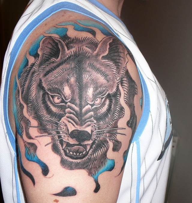 Tatuaggio colorato sul deltoide la faccia del lupo aggressivo