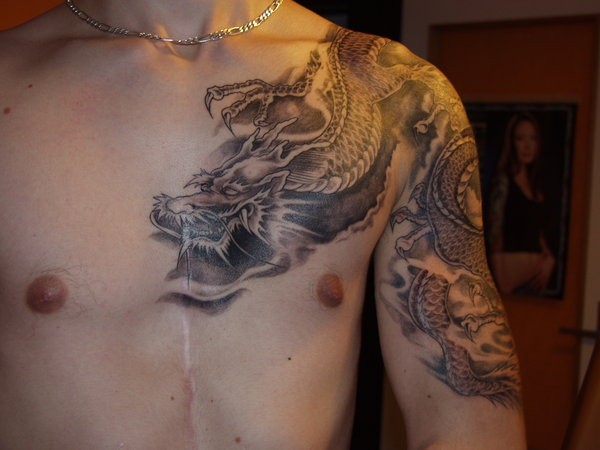 Tatuaggio sul petto e il braccio il dragone grande
