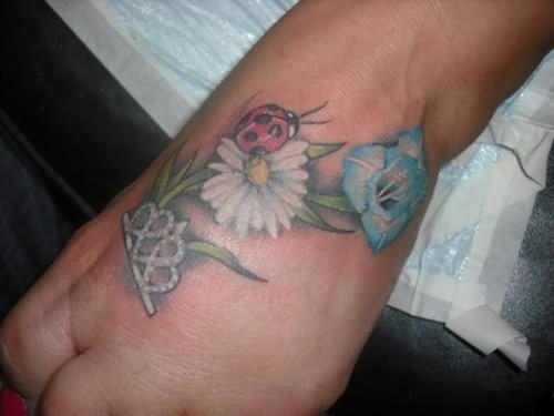 Tatuaggio bellissimo sul mano la coccinella rossa sul fiore bianco
