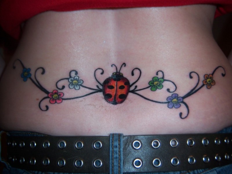 Marienkäfer und Blumen Tattoo am unteren Rücken