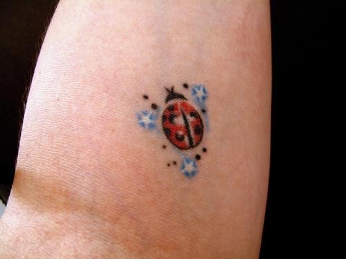 Tatuaje  de mariquita y estrellas azules