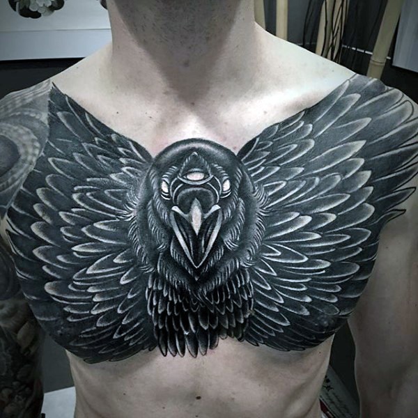 Large black ink chest tattoo of big crow with tree eyes