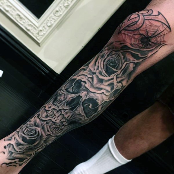 Large black ink leg tattoo of human skull stylized with roses