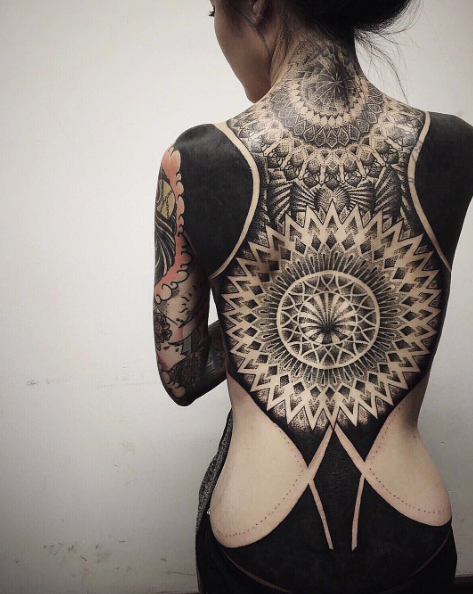 Large blackwork style whole back tattoo combined with ornamental flowers