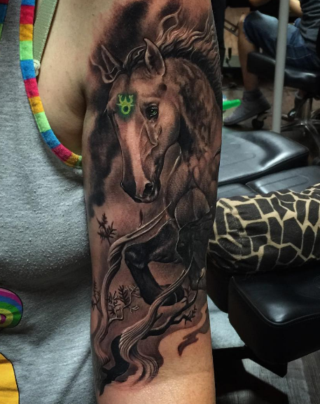 Large colored arm tattoo of fantasy horse with mystical symbol