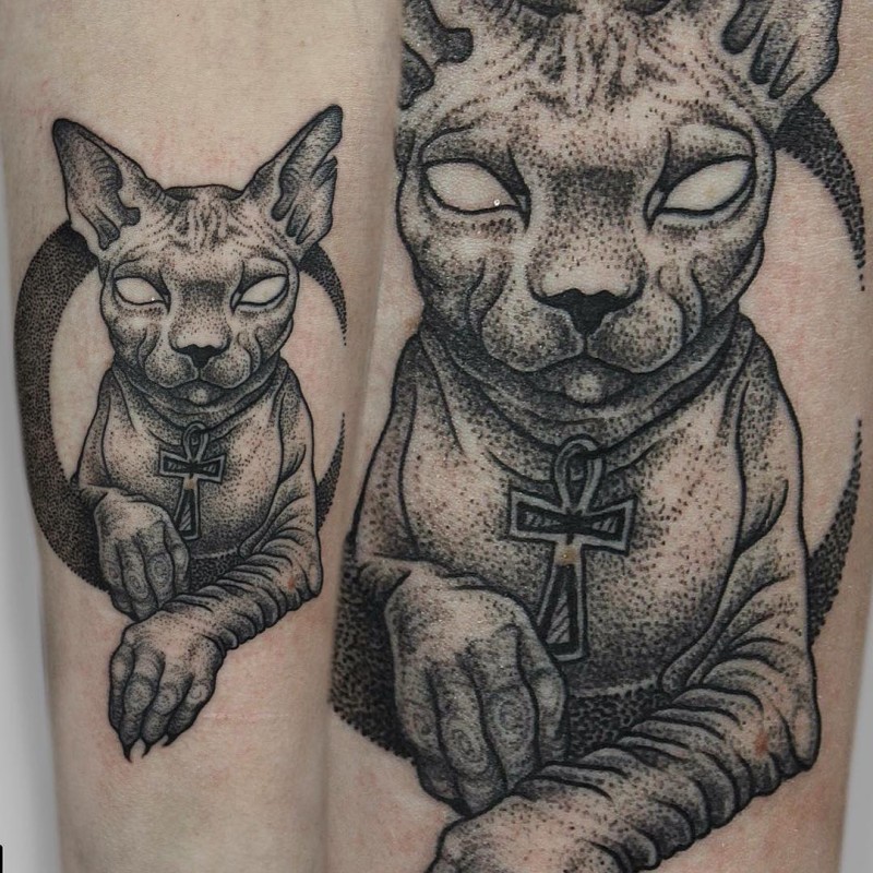 Large dot style arm tattoo of mysterious sphinx cat with large cross