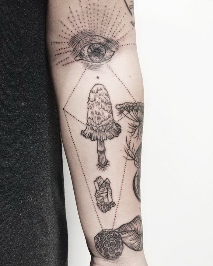 Large forearm tattoo of human eye with mushroom and crystal