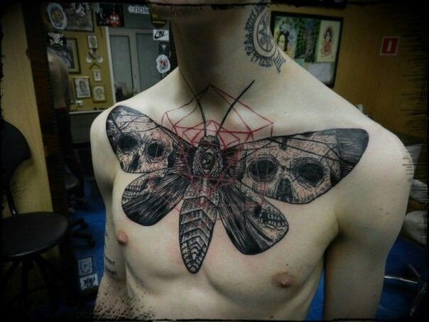 Large illustrative style chest tattoo of big butterfly stylized with human skulls