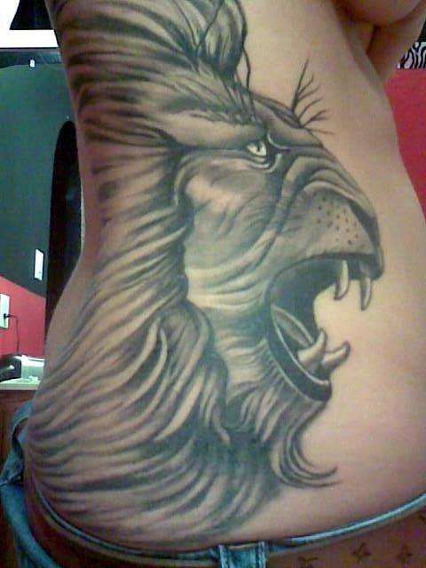 Un tatuaje grande a todo el costado de la cabeza de un leon rugiendo detallado