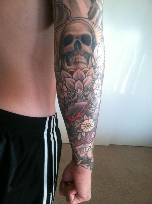 Large skull with flowers forearm tattoo