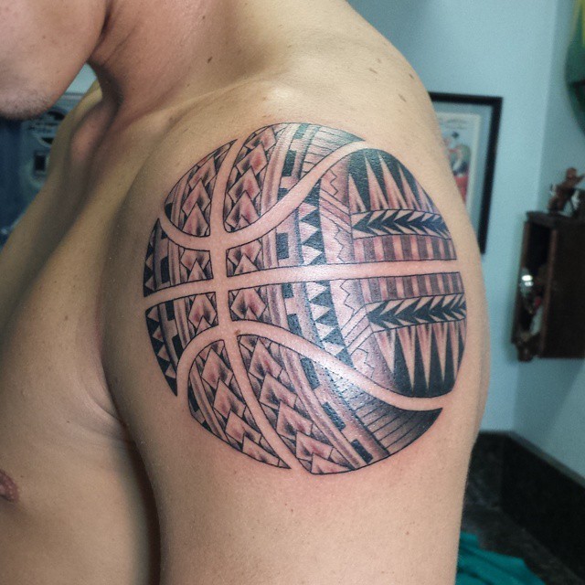 Large unusual looking basketball tattoo on shoulder stylized with Polynesian ornaments