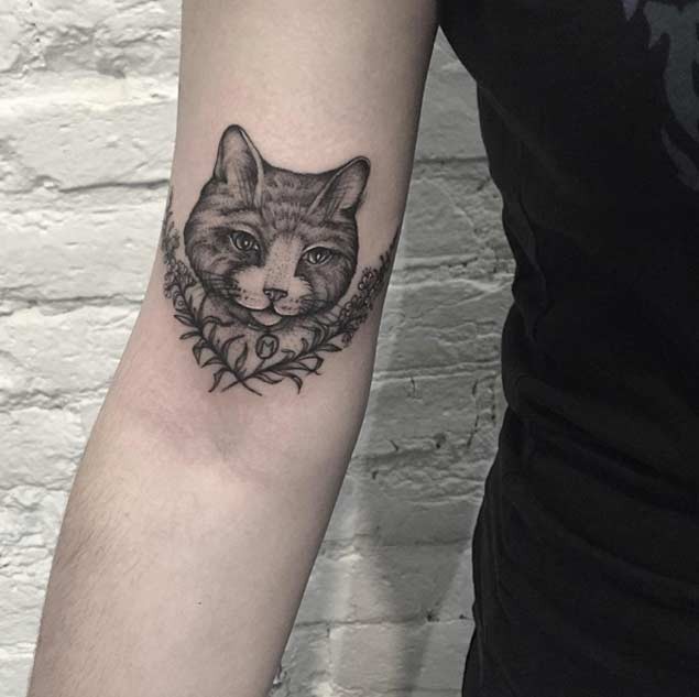 Tatuaje en el brazo, cara de gato bonito con dos ramitas
