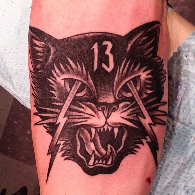 Little black and white crazy cat tattoo on forearm with lightning and number