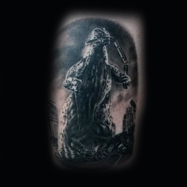 Little black and white evil Godzilla in city tattoo on thigh
