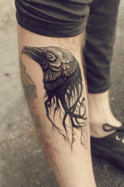 Little black and white mystical crow head tattoo on leg stylized with roots