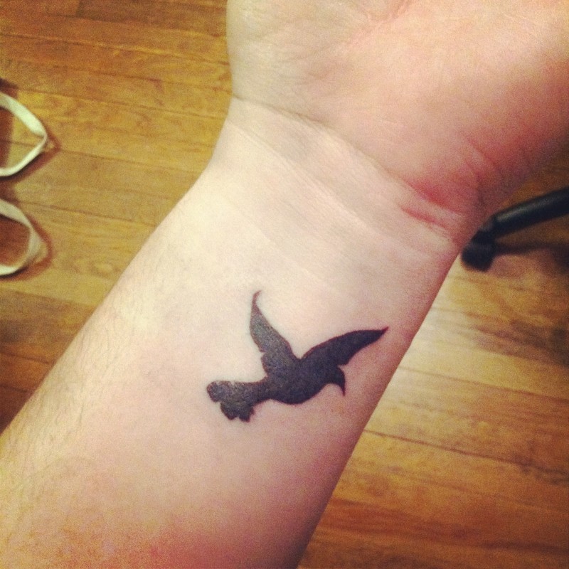 piccolo uccello nero tatuaggio disegno su polso