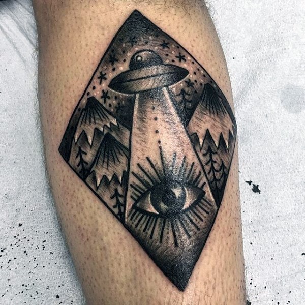 Tatuaje en la pierna, nave extraterrestre con ojo misterioso y montañas
