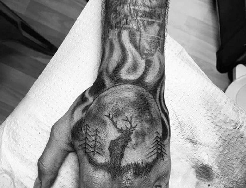 Little black ink night forest tattoo on hand stylized with elk silhouette