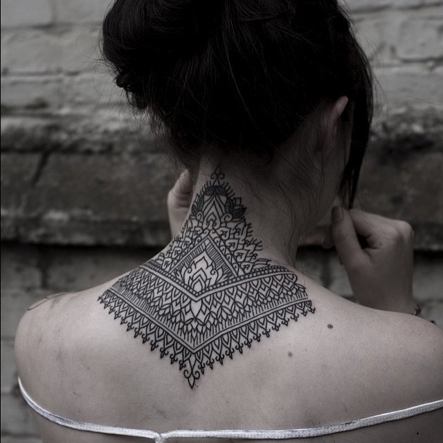 Little black ink ornamental tattoo on neck