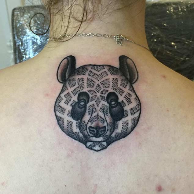 Little black ink panda bear head tattoo on upper back stylized with tribal ornaments