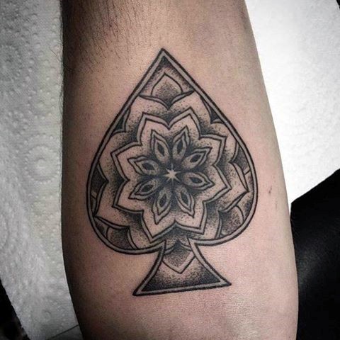 Little black ink spades symbol stylized with flower tattoo on hand
