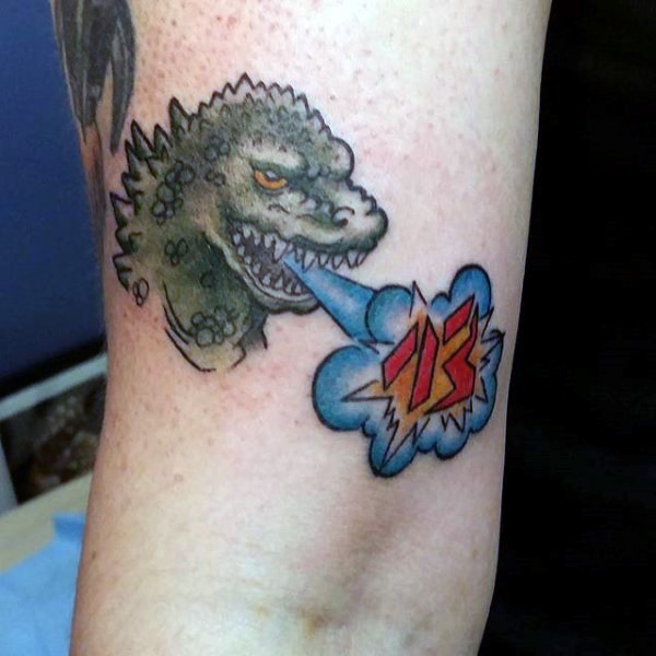 Pequeño tatuaje Godzilla con el número en color en el codo