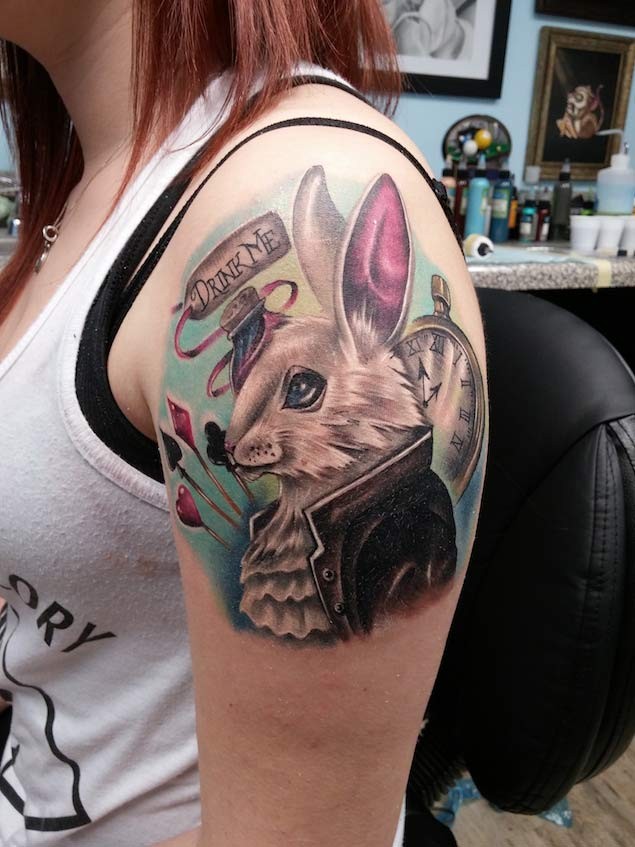 Little cartoon like colored rabbit tattoo on shoulder with clock and lettering