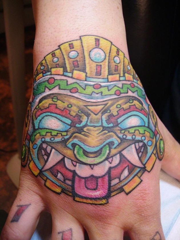 Tatuaje en la mano,  cara tribal de varios colores