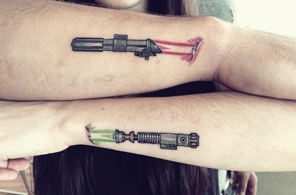 Kleines cartoonisches gefärbtes Tattoo an Handgelenken mit Lichtschwertern unter der Haut