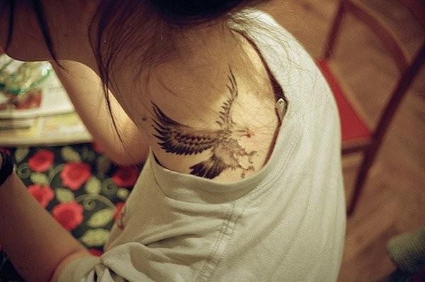 Tatuaje pequeño muy detallado el águila volando en la nuca