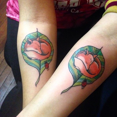 Little colored identical sleeping fox on leaf couple tattoo on forearm combined with ladybug