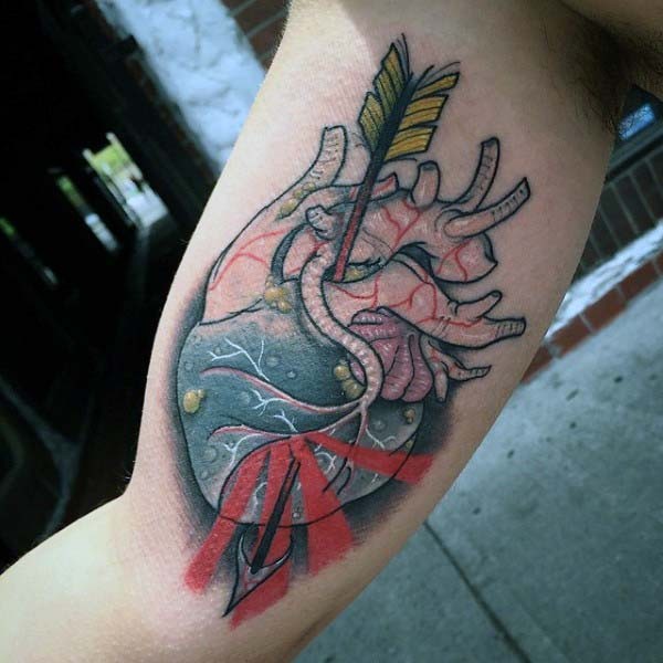 Little colored realistic heart with arrow tattoo on arm