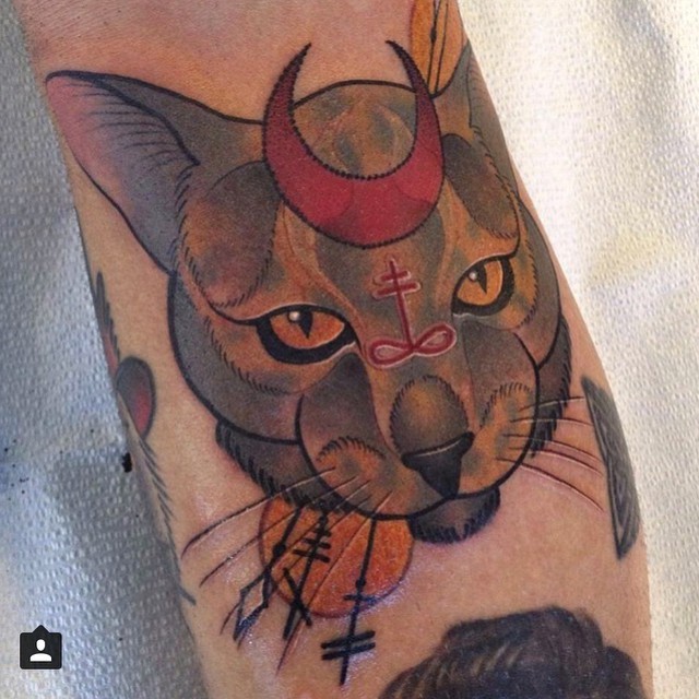 Little colored steady cat tattoo on forearm stylized with cult symbols