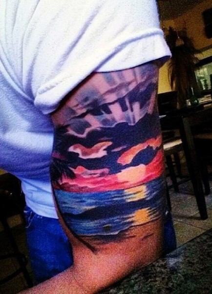 Tatuaje en el brazo, océano a puesta del sol, paisaje pintoresco