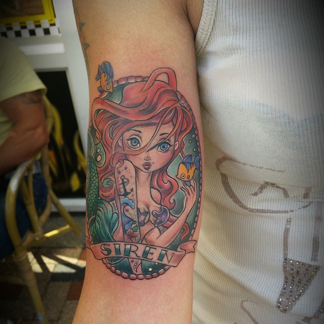 Little cute looking colored mermaid portrait tattoo on arm with lettering