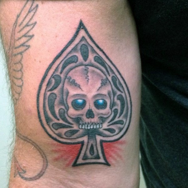 Little fantasy spades symbol stylized with skull tattoo on arm