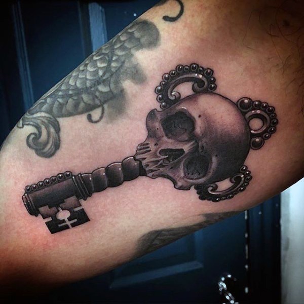 Tatuaje en el muslo, llave único precioso decorado con cráneo